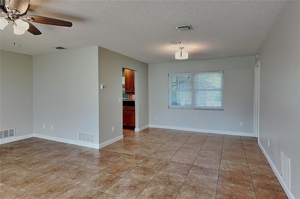 An empty room features tan tile flooring, light gray walls, a ceiling fan, and a window — 1016 MANCHESTER CIRCLE, WINTER PARK, FL