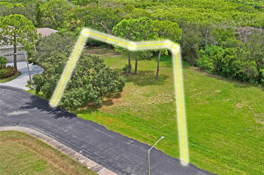 An aerial view shows a vacant residential lot outlined in yellow near a paved cul-de-sac — 3034 SHEPPARDS CROOK, HOLIDAY, FL
