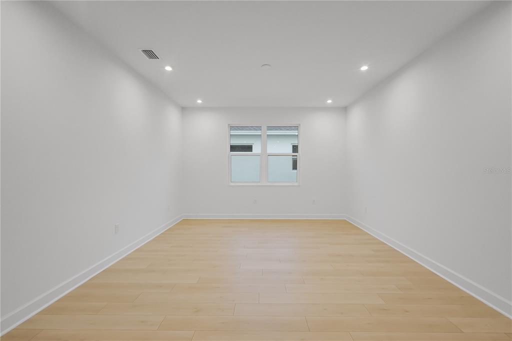 An empty room features white walls, recessed lighting, and light-colored wood-look flooring — 1615 BELLAGIO LOOP, TAVARES, FL