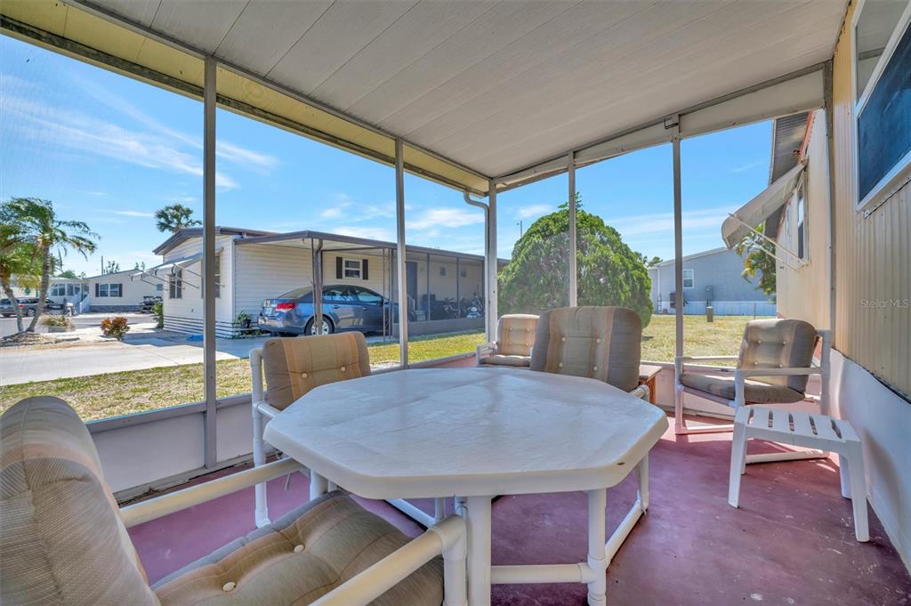 A screened-in porch features a white table, cushioned chairs, and a red concrete floor — 104 SAINT KITTS WAY, APOLLO BEACH, FL