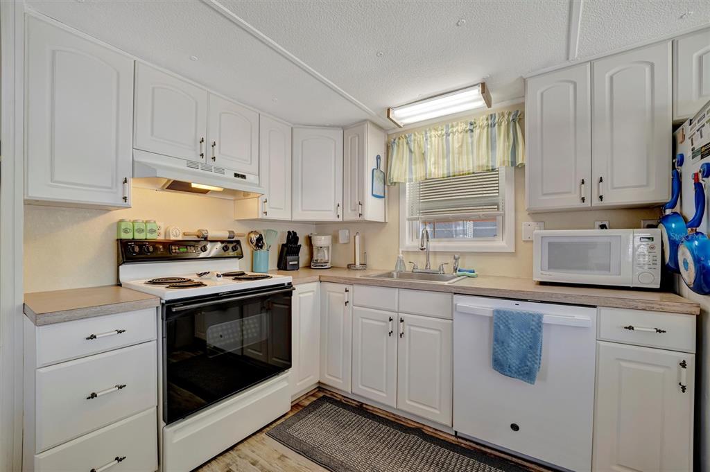 A kitchen with white cabinets, a white stove, a dishwasher, and a window with curtains — 104 SAINT KITTS WAY, APOLLO BEACH, FL