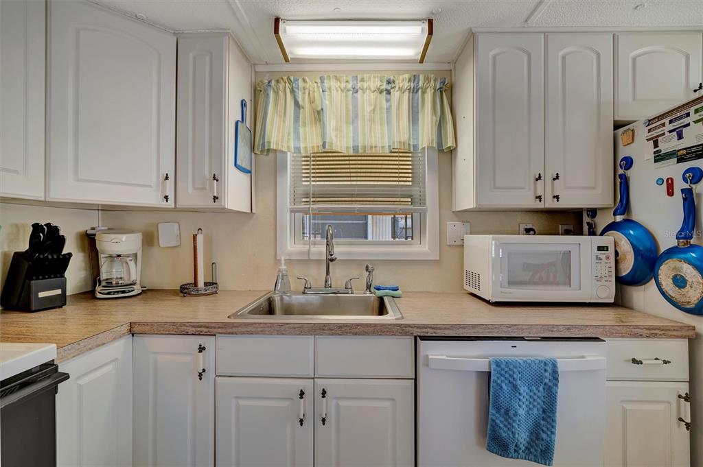 A kitchen features white cabinets, a stainless steel sink, a microwave, and a dishwasher — 104 SAINT KITTS WAY, APOLLO BEACH, FL