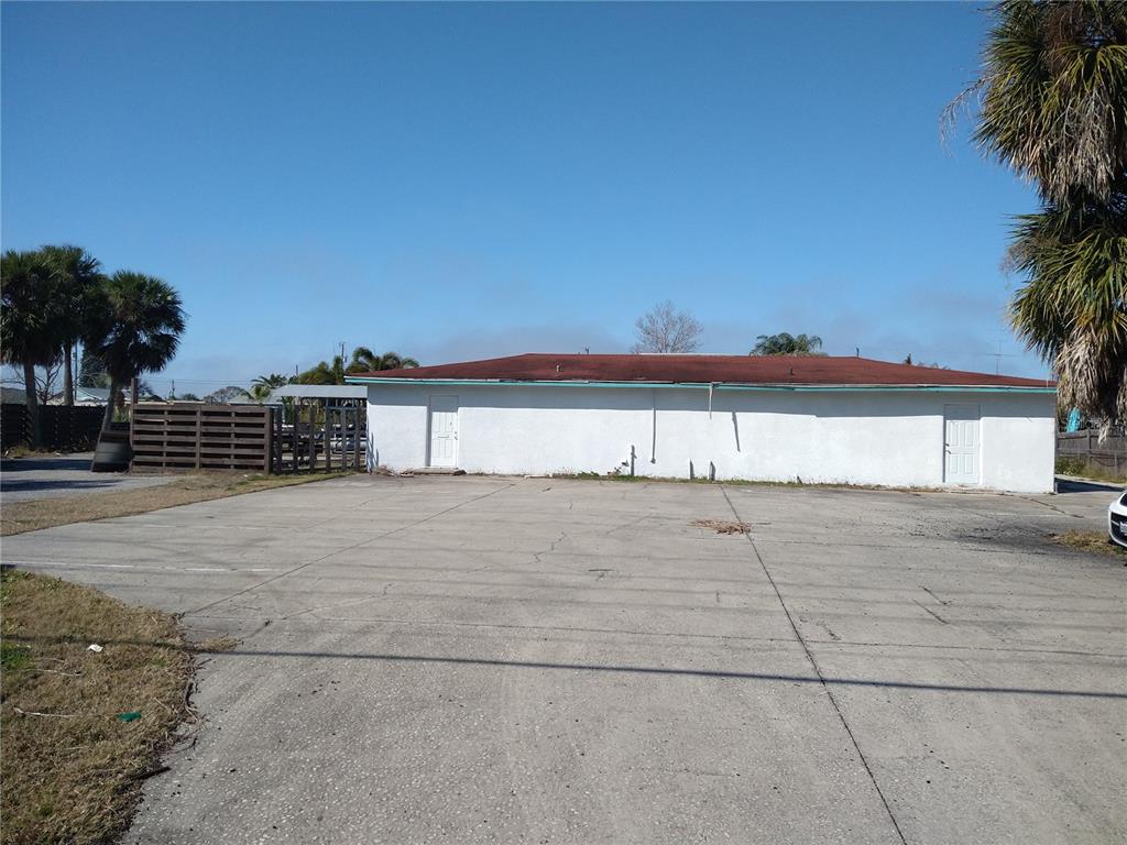 A white, single-story building with a red roof sits behind a large concrete parking lot — 13923 OLD DIXIE HIGHWAY, HUDSON, FL