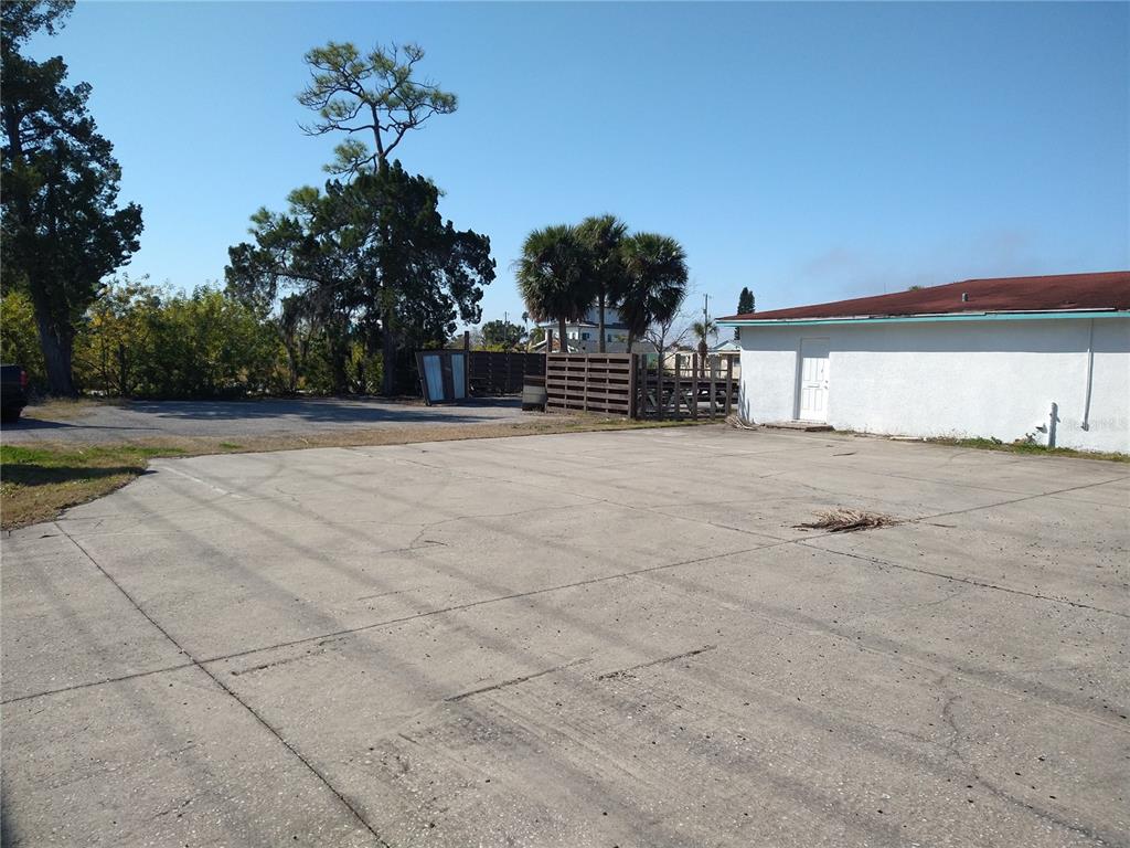 A large concrete parking lot sits beside a white building with a red roof — 13923 OLD DIXIE HIGHWAY, HUDSON, FL