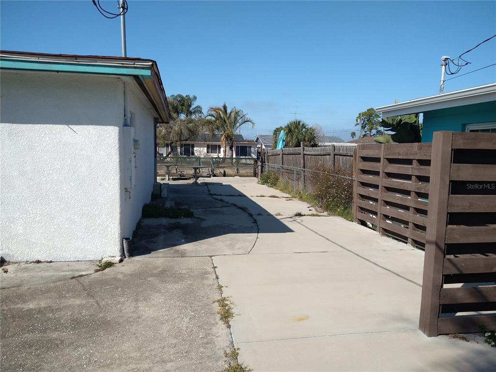 A concrete driveway runs between a white building and a brown wooden privacy fence — 13923 OLD DIXIE HIGHWAY, HUDSON, FL