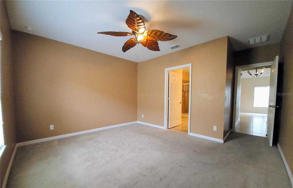 A bedroom with tan walls, beige carpeting, and a tropical-style ceiling fan — 316 ANDALUSIA LOOP, DAVENPORT, FL