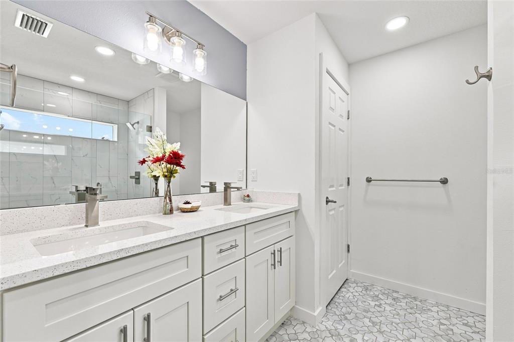 A bathroom with a double vanity, white cabinets, quartz countertops, and a tiled floor — 2984 SE 140TH LANE, SUMMERFIELD, FL