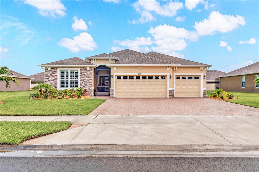 A single-story house with a stone facade, a three-car garage, and a brick paver driveway — 6691 CAMEO DRIVE, GRANT, FL