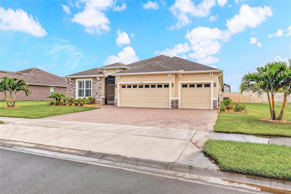 A single-story suburban house with a tan stucco exterior, stone accents, and a paved driveway — 6691 CAMEO DRIVE, GRANT, FL