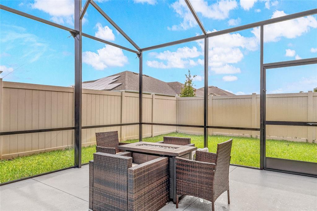 A screened-in patio features a wicker furniture set with a fire pit table — 6691 CAMEO DRIVE, GRANT, FL