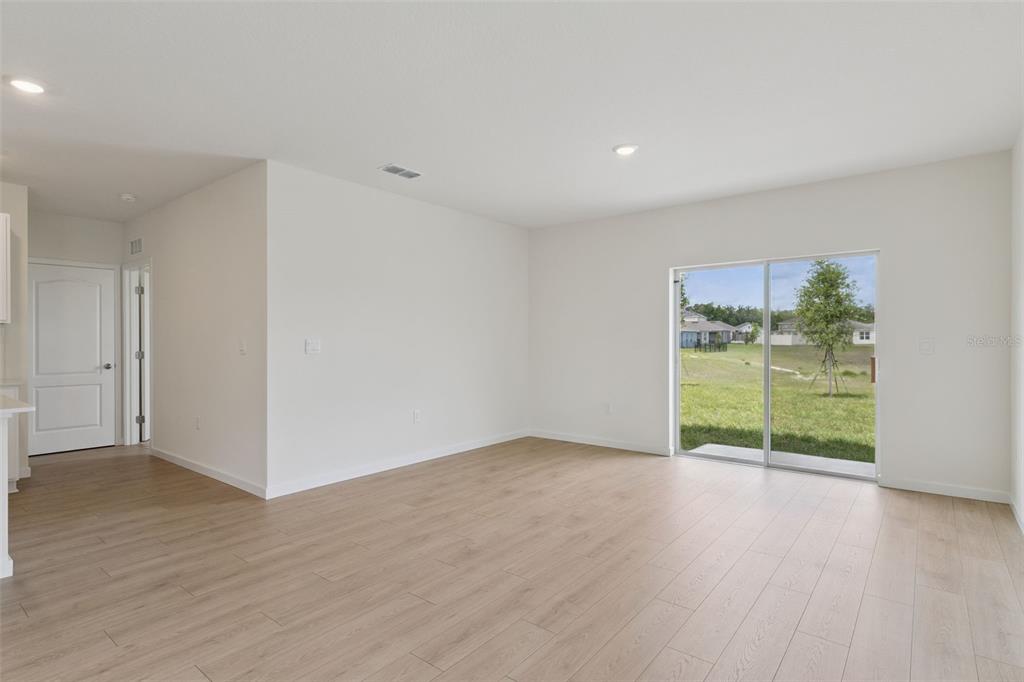 An empty room with light wood-look flooring, white walls, and a sliding glass door — 941 BLUET DRIVE, PORT ORANGE, FL