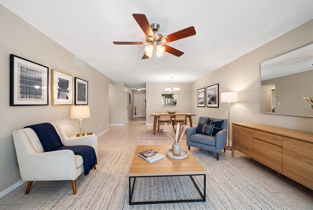 A living room with a coffee table, two armchairs, a dining area, and tile flooring — 330 PROMENADE DRIVE UNIT 206, DUNEDIN, FL