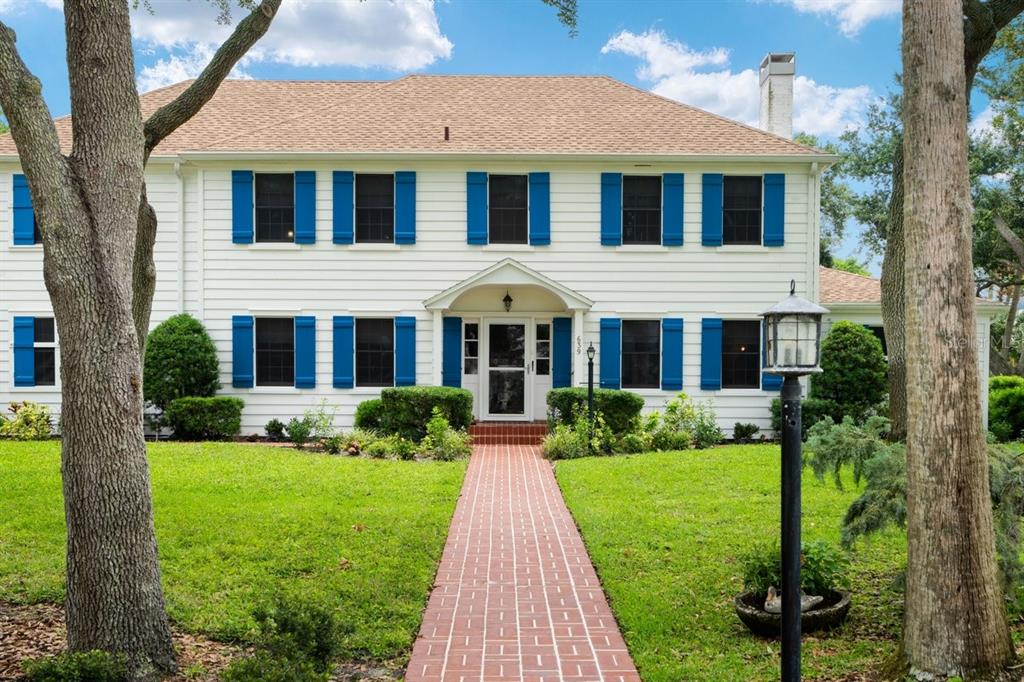 A two-story white house with blue shutters and a brick walkway leading to the entrance — 639 & 659 JOHN ANDERSON DRIVE, ORMOND BEACH, FL