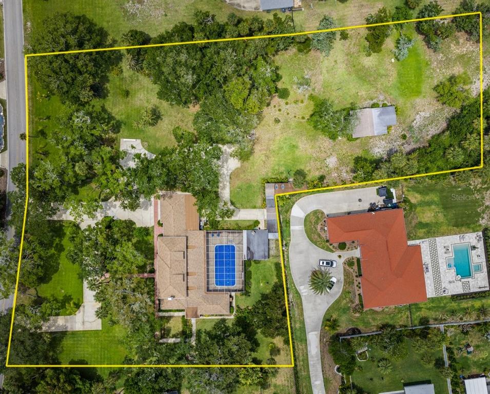 An aerial view shows a large residential property with a pool and extensive wooded grounds — 639 & 659 JOHN ANDERSON DRIVE, ORMOND BEACH, FL