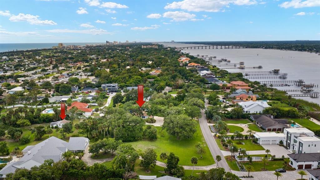An aerial view shows two houses marked with red arrows amidst a lush, tree-filled landscape — 639 & 659 JOHN ANDERSON DRIVE, ORMOND BEACH, FL