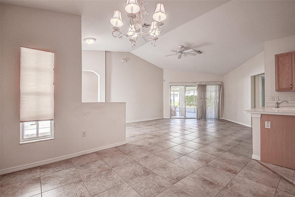 An open-concept living and dining area features tile flooring, a chandelier, and sliding glass doors — 29417 CADDYSHACK LANE, SAN ANTONIO, FL