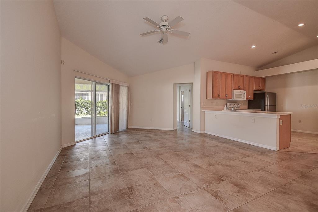 An open-concept living area features tile flooring, a ceiling fan, and an adjacent kitchen — 29417 CADDYSHACK LANE, SAN ANTONIO, FL
