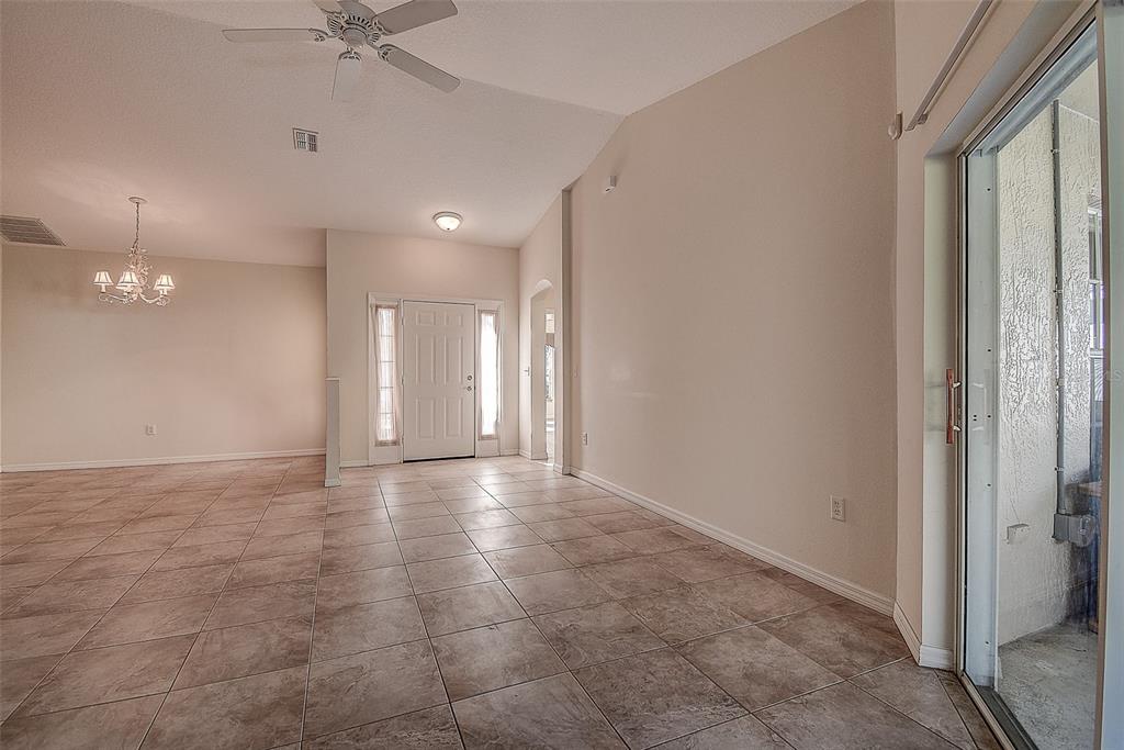 An interior view of a tiled entryway and dining area with a white front door — 29417 CADDYSHACK LANE, SAN ANTONIO, FL