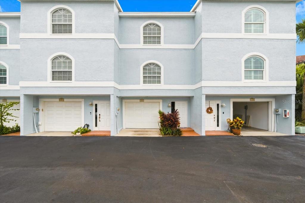 A three-story light blue townhouse complex with three garage bays and arched windows — 751 PINELLAS BAYWAY  S UNIT 19, TIERRA VERDE, FL