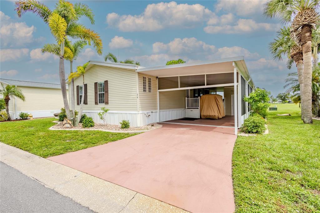 A light-colored mobile home features a covered carport, a paved driveway, and palm trees — 2100 KINGS HIGHWAY UNIT 314, PORT CHARLOTTE, FL