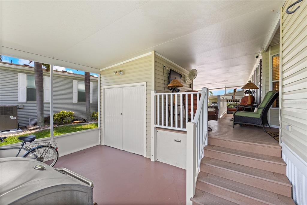 A covered porch features a wooden deck, stairs, a storage closet, and outdoor seating — 2100 KINGS HIGHWAY UNIT 314, PORT CHARLOTTE, FL