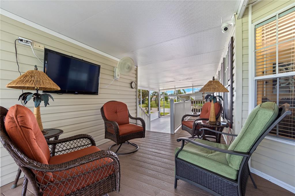 A covered outdoor porch features wicker furniture, a wall-mounted television, and a ceiling fan — 2100 KINGS HIGHWAY UNIT 314, PORT CHARLOTTE, FL
