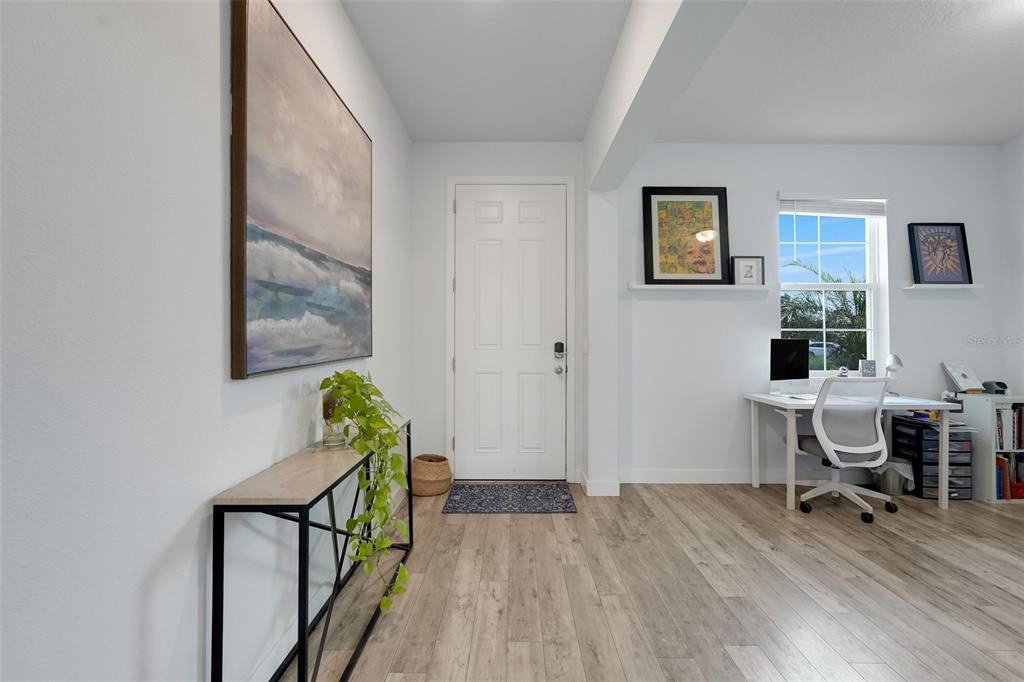 A bright entryway features light wood-look flooring, a white front door, and a home office area — 1750 STANDING ROCK CIRCLE, OAKLAND, FL