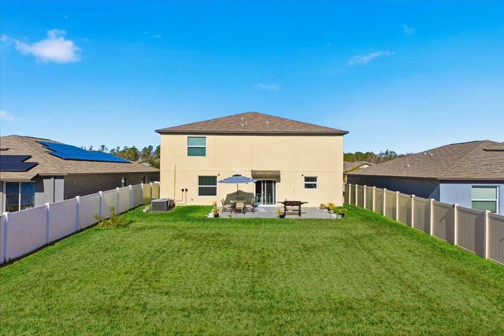 The rear exterior of a two-story house features a patio, lawn, and vinyl fencing — 2175 OLD MINING ROAD, LAKELAND, FL