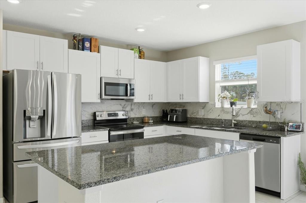 A kitchen with white cabinets, granite countertops, stainless steel appliances, and a central island — 2175 OLD MINING ROAD, LAKELAND, FL