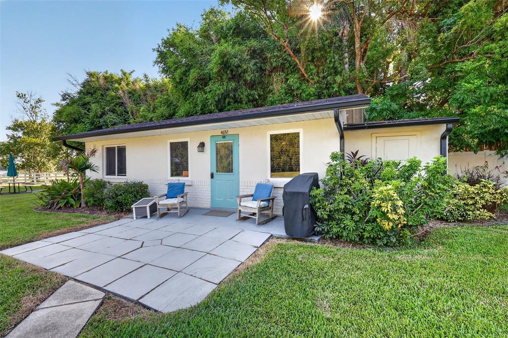 A small, single-story house with a light-colored exterior, a teal front door, and a patio — 4634 BIGLER LANE, MOUNT DORA, FL