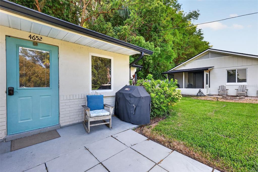 A teal door and a patio chair sit on a concrete patio beside a grill — 4634 BIGLER LANE, MOUNT DORA, FL