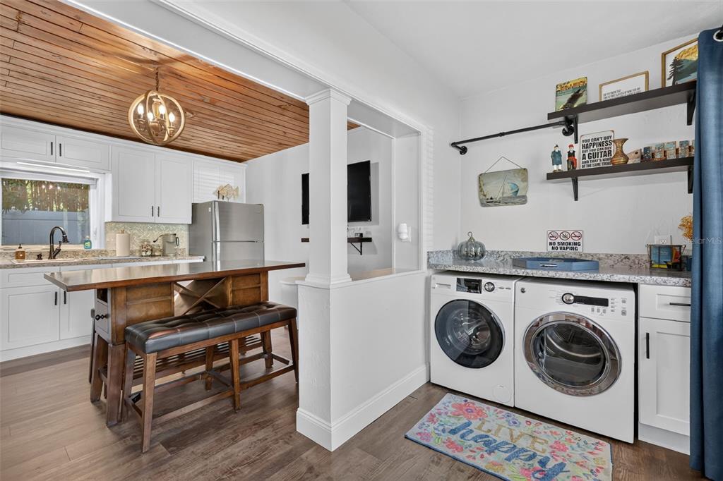 A kitchen with a wood-paneled ceiling and an adjacent laundry area with white cabinets — 4634 BIGLER LANE, MOUNT DORA, FL