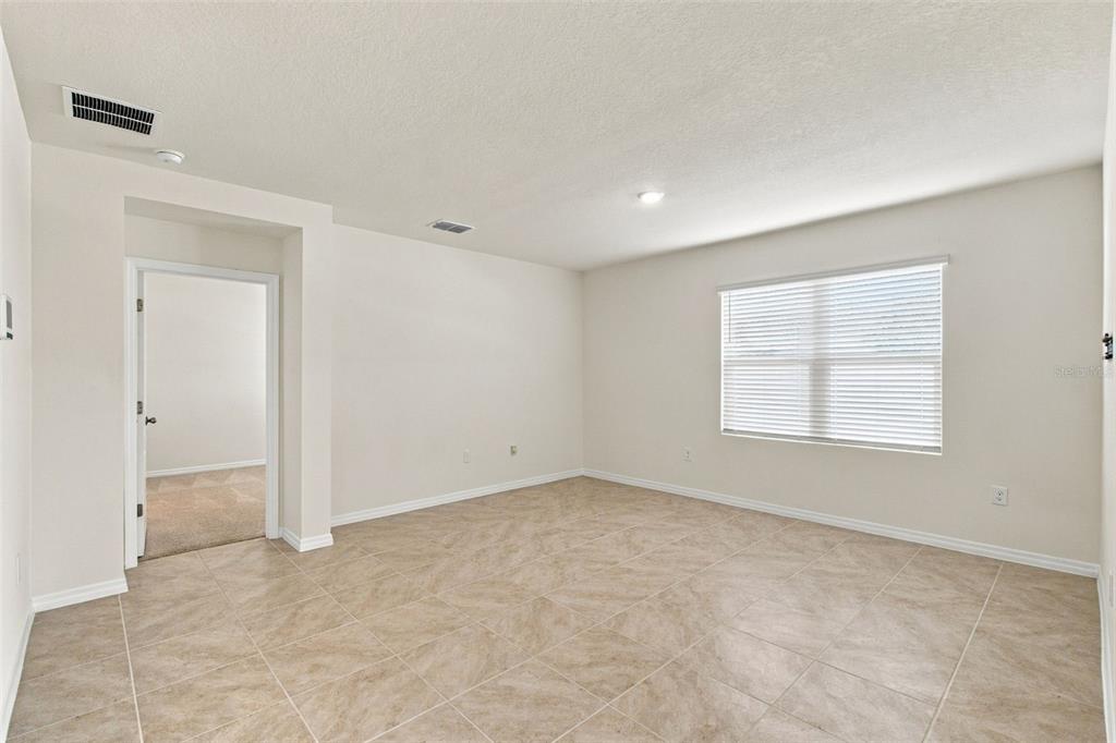 A room with beige tile flooring, neutral walls, a window with blinds, and a doorway — 2566 TRINIDAD ROAD, HAINES CITY, FL