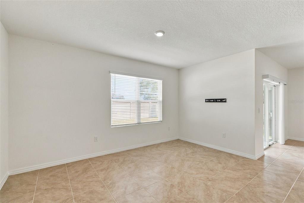 An empty room with white walls, tile flooring, a window with blinds, and sliding glass doors — 2566 TRINIDAD ROAD, HAINES CITY, FL