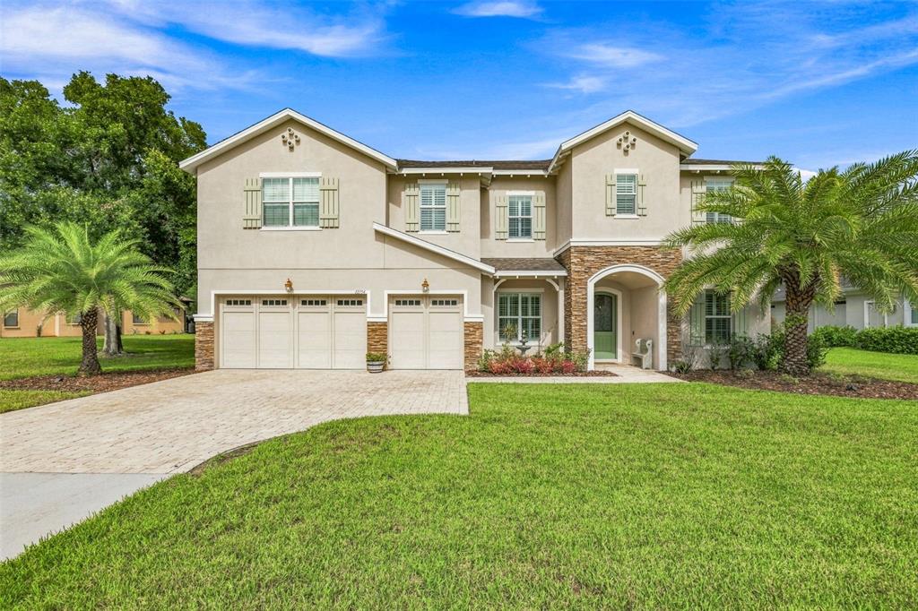 A two-story suburban house features a three-car garage, stone accents, and two palm trees — 12754 SERONERA VALLEY COURT, SPRING HILL, FL