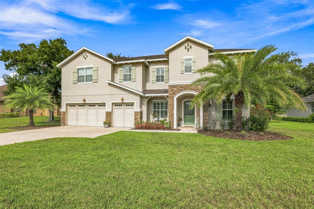 A two-story suburban house with a stone facade, three-car garage, and a palm tree — 12754 SERONERA VALLEY COURT, SPRING HILL, FL