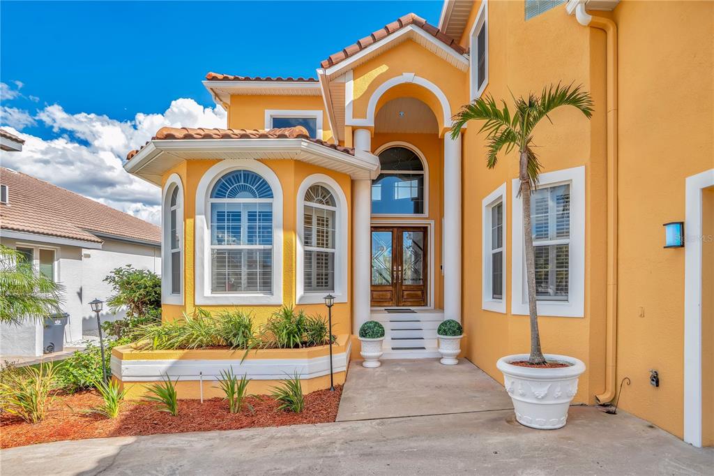 The exterior of a yellow two-story house features a covered entryway with white columns — 934 SYMPHONY ISLES BOULEVARD, APOLLO BEACH, FL