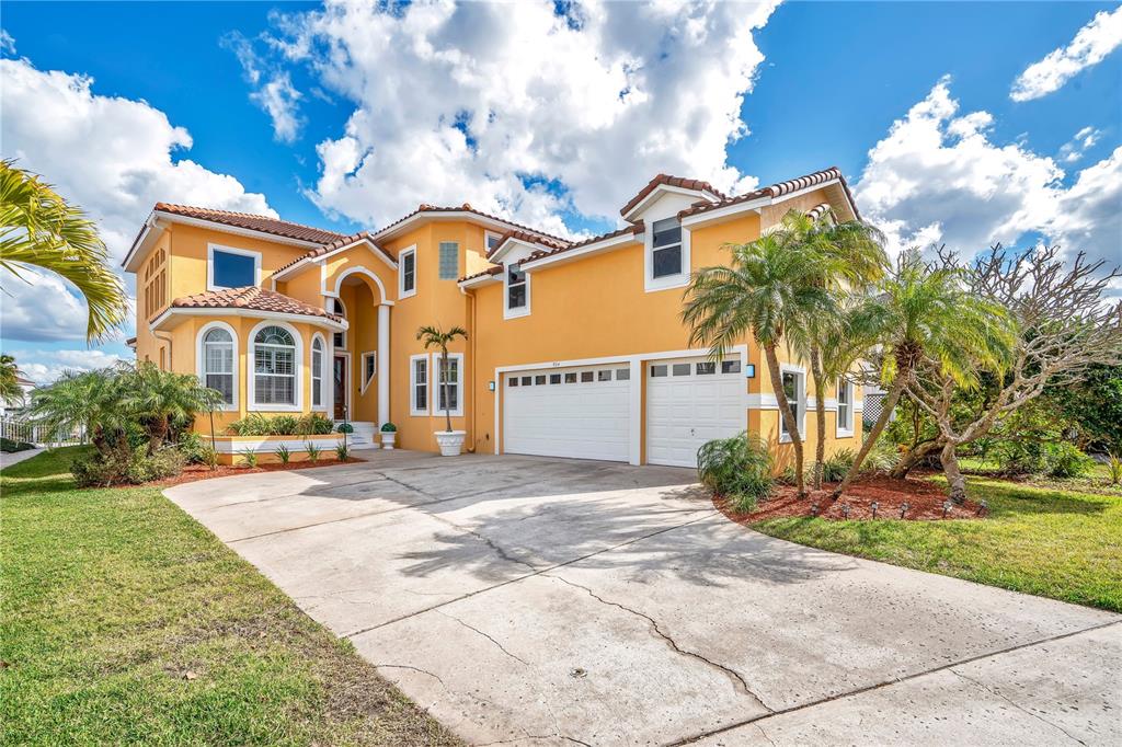 A two-story yellow house with a tile roof, a three-car garage, and a concrete driveway — 934 SYMPHONY ISLES BOULEVARD, APOLLO BEACH, FL
