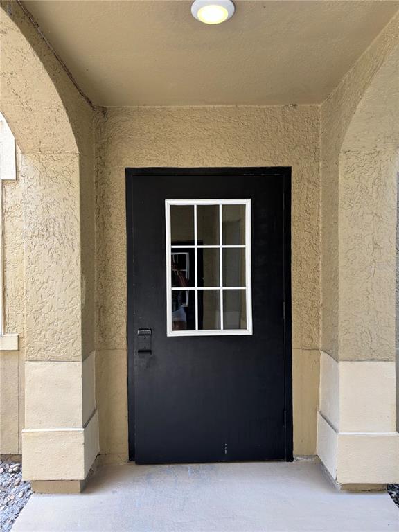 A black door with a white-framed window sits under a covered entryway with stucco walls — 103 VISTA VERDI CIRCLE UNIT 229, LAKE MARY, FL