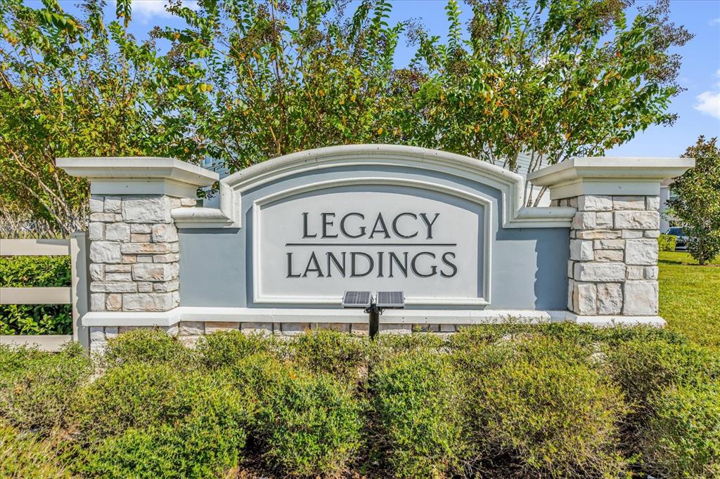 A stone and stucco monument sign for Legacy Landings sits in a landscaped yard — 1108 SAND TORCH CIRCLE, DAVENPORT, FL
