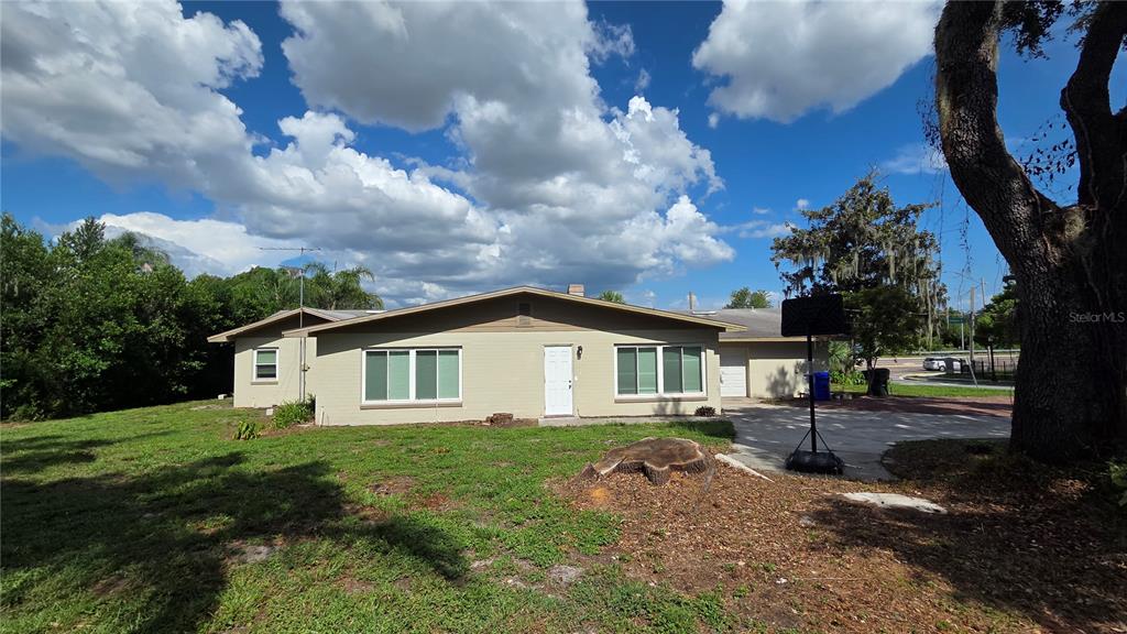 A single-story house with a tan exterior, a white front door, and a large tree stump — 925 SIKES BOULEVARD, LAKELAND, FL