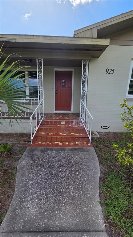 A concrete walkway leads to a set of tiled steps and a red front door — 925 SIKES BOULEVARD, LAKELAND, FL