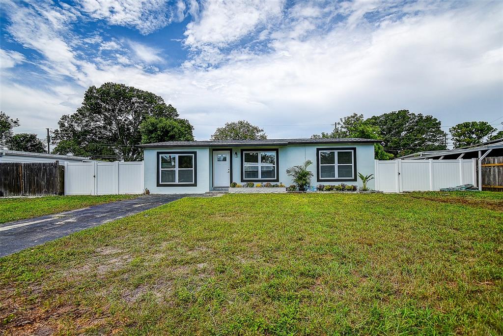 A light blue single-story house with a white fence and a paved driveway — 7580 MEADOWLAWN DRIVE N, ST PETERSBURG, FL