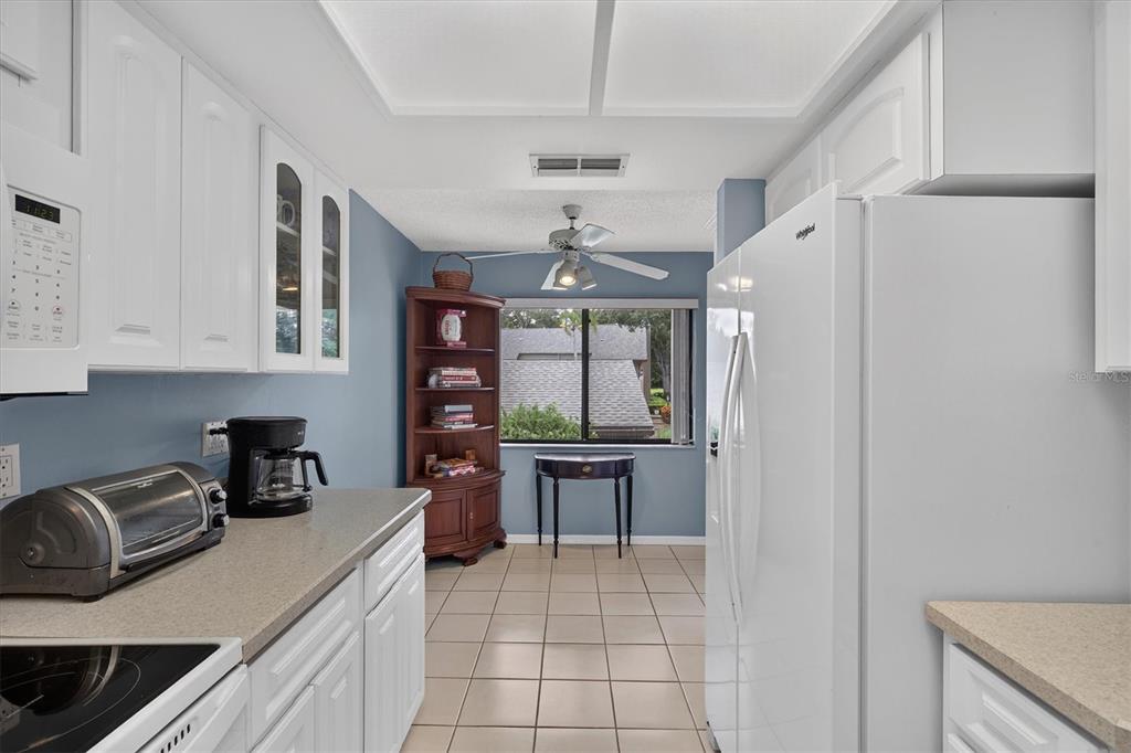 A kitchen with white cabinets, light countertops, tile flooring, and a window overlooking a roof — 3167 LANDMARK DRIVE UNIT 821, CLEARWATER, FL