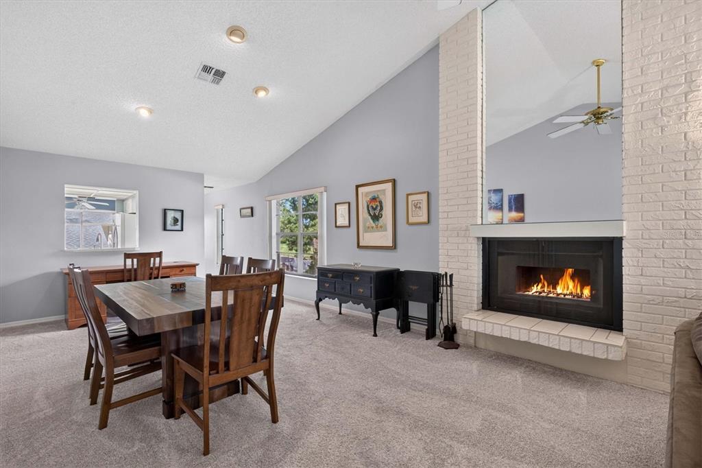A dining room with a wooden table, carpeted floors, and a brick fireplace with a mirror — 3167 LANDMARK DRIVE UNIT 821, CLEARWATER, FL