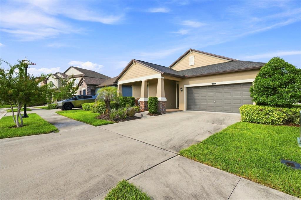 A covered front porch features a small glass table, two wicker chairs, and a dark door — 9189 SHADYSIDE LANE, LAND O LAKES, FL
