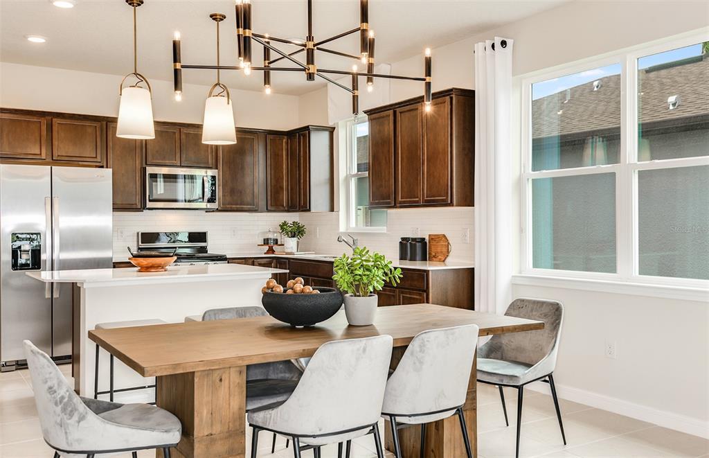 A kitchen with dark wood cabinets and a dining area with a wooden table — 12518 ADOBE STREET, PARRISH, FL