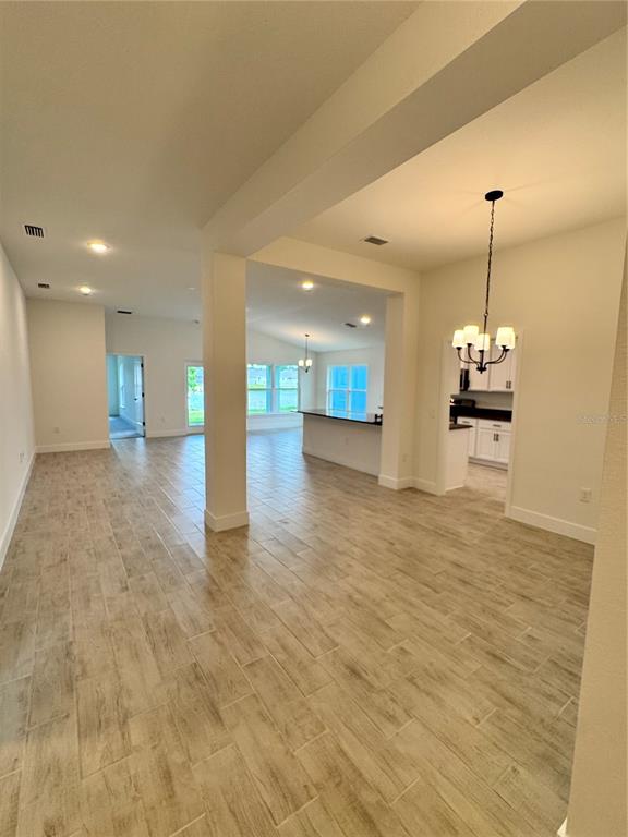 An open-concept living area features light wood-look tile flooring and a dining room chandelier — 2659 AVERLAND LOOP, NORTH PORT, FL