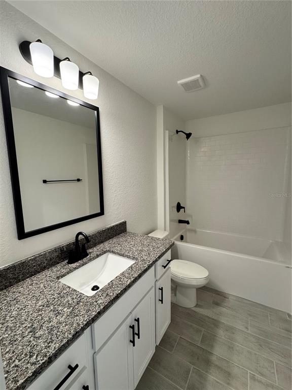 A bathroom features a granite vanity, white cabinets, a black-framed mirror, and a tub-shower combo — 2659 AVERLAND LOOP, NORTH PORT, FL