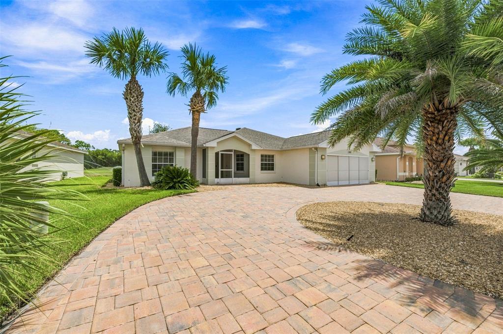 A single-story house with a paved driveway, palm trees, and a screened front entryway — 10345 COLLAR DRIVE, SAN ANTONIO, FL